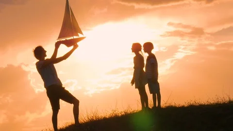 Model of a sailboat. A man is holding a ship model against the sky.  Stock Footage 79114202