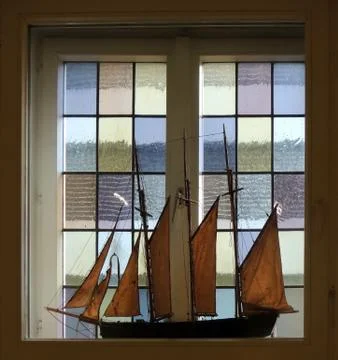 Model of sailboat on window with colored glasses Stock Photos