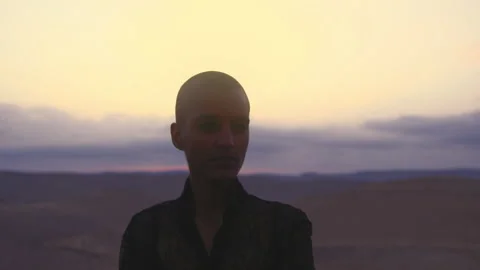 Model with shaved head posing in front of the camera in desert Stock Footage 275644236