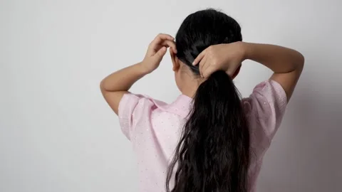 The model is shown from behind, gathering her long, dark hair with both hands. Stock Footage 319824183