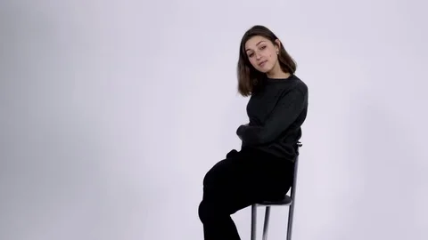 The model sits on a chair with an indifferent expression Stockbeeldmateriaal 81810158