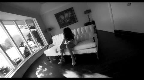 Model sits on a sofa near a large window Vídeos de archivo 45829547
