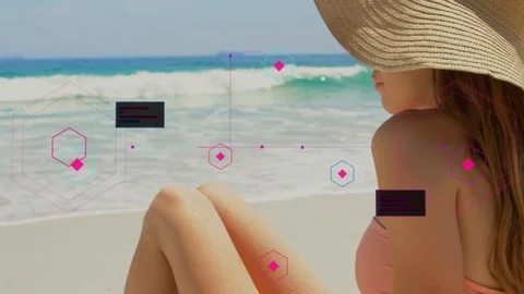 Model sitting on beach while camera panning upward, pink shapes covering hat, Video stock 333925097