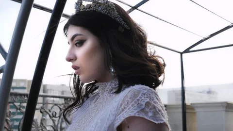 Model stands on balcony in white lacy gown with hairstyle Stock Footage 107960609
