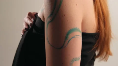 The model stands in the studio and shows a tattoo Stock Footage 184151932