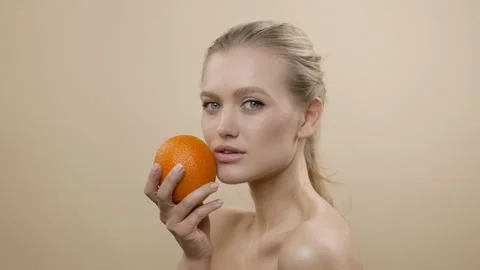 Model In Studio Posing. Young Blonde With Long Hair Holding An Orange. 스톡 동영상 152852675