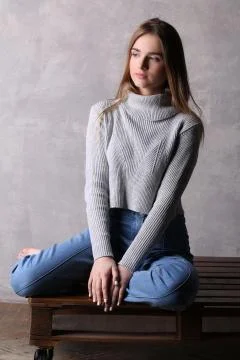 Model in sweater sitting on a deck. Gray background Stock Photos