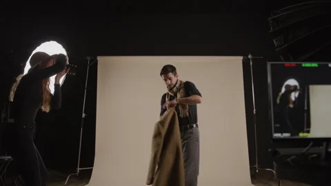Model Takes Off Coat While Posing For Photographer In Studio Stock Footage 270396717