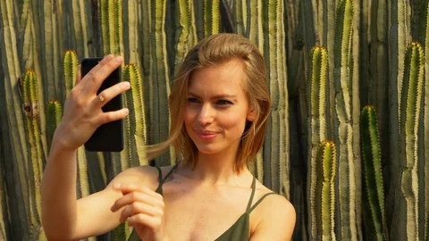 Model Taking a Top View Selfie in Front of Cacti Stock Footage 114175330
