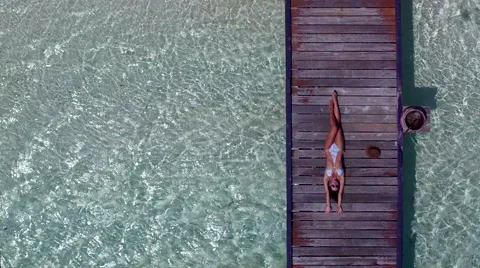 Model tanning on jetty in the crystal clear water in Maldives- 4K Drone Video 動画素材 64969229