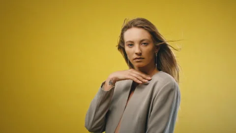Model with tattoo looking straight at camera yellow background Stock Footage 275628385