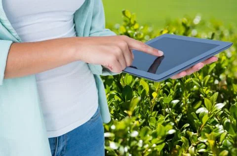 Model is touching tablet computer screen against plant background 写真素材