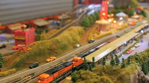 A model toy train passes a town with a carnival in a railroad set Stock Footage 52551251