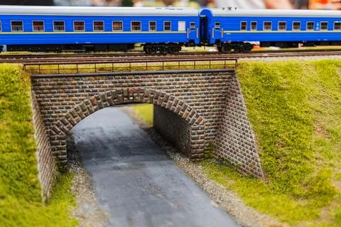 Model train on brick bridge tracks, under naturalistic lighting, traversing l Stock Photos