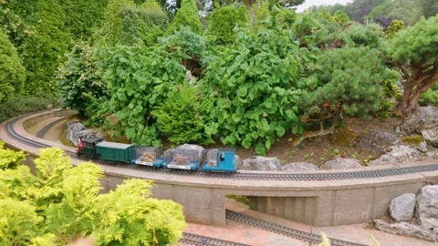 Model train carrying toy dinosaurs on miniature railway at Godshill model Stock Footage 340189453