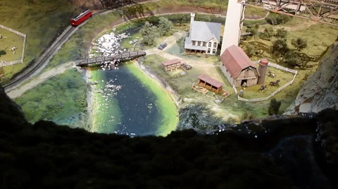 Model Train rides by a model river and a foreground waterfall Stock Footage 63236583
