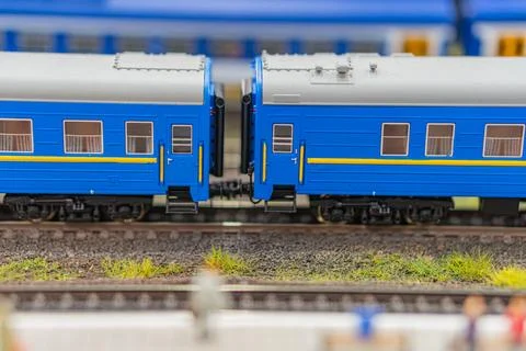 Model train set on blurred background, two blue passenger cars with yellow st Stock Photos