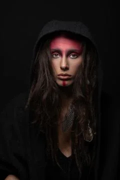 Model with tribe red make-up, dreadlocks, feather attached to her hair hiding Stock Photos