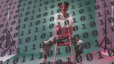 Model unzipping jacket showing dark top, shifting on pink chair while binary Stock Footage 333790043