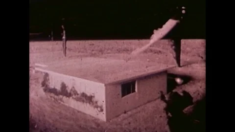 A model village is blown away by a nuclear bomb blast in the Nevada desert. Stock Footage 106905777