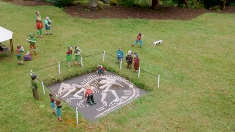 Model village dinosaur dig with miniature archaeologists around fossil Stock Footage 340051265