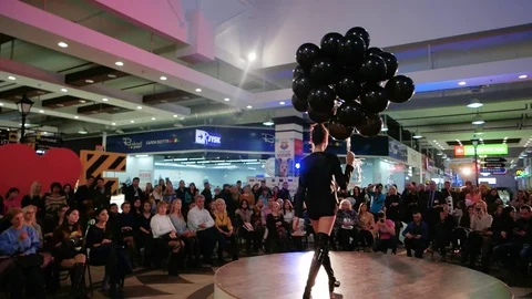 Model walking runway holding dark balloons, young girl in blak defile down Stock Footage
