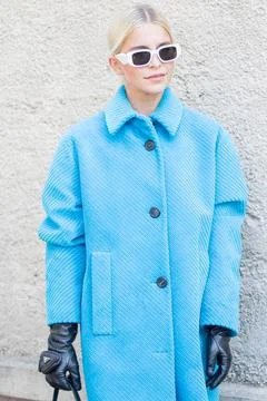 Model wears a light blue coat and a pair of sunglasses Stock Photos