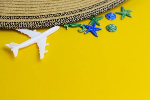Model of white airplane, beach hat and starfishes on a yellow background Stock Photos
