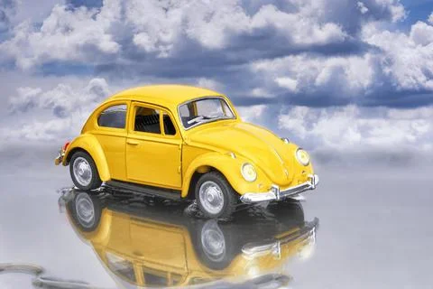 Model of a yellow Beetle parked on a puddle and the lights on, we can see its Stock Photos