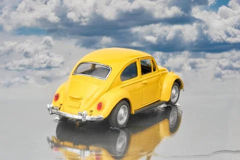 Model of a yellow Beetle seen from behind parked in a puddle Stock Photos