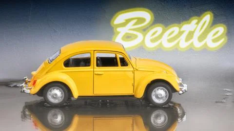 Model of a yellow Beetle seen from the side parked in a puddle Stock Photos