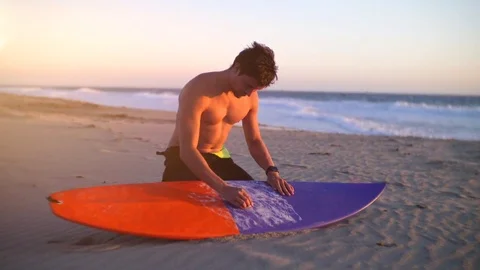 Model young surfer waxing surf board  in Zuma beach. How to wax hard top? Stock Footage 82947194