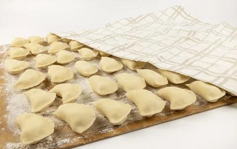 Modelling dumplings. A board with dumplings is half covered with a towel. Stock Photos