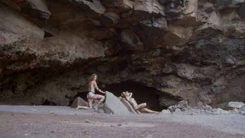 Models covered in sandlike body paint near a cave Video stock 101443095