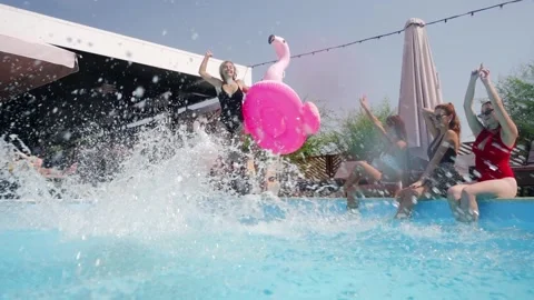 Models sit and dance with inflatable tubes, friends jump into swimming pool blue 스톡 동영상 272264730