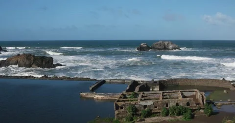 Moderate size surf breaking along the sea wall at Sutro Baths in San Francisco.  Stock Footage 61805983