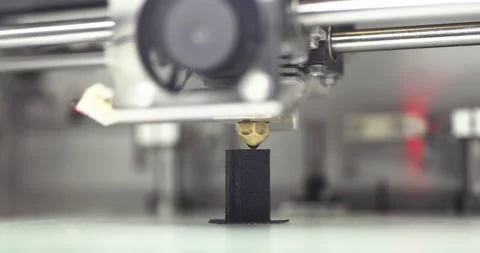 Modern 3d printer is printing black plastic object or detail, closeup side view. Stock Footage 142699987