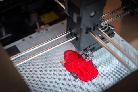 Modern 3D printer printing small red figure, closeup view from above Foto stock