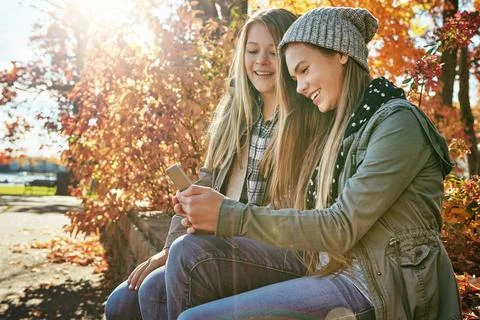 Modern age connections. two young friends using a mobile phone together while Stock Photos