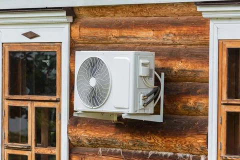 Modern air conditioner unit installed on the exterior wall of a rustic log .. Stock-Fotos