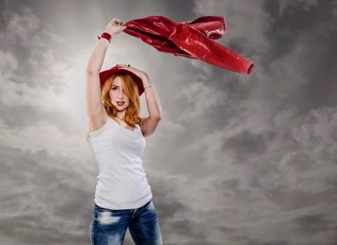 Modern amazon. Red-haired young woman in a red hat waving a leather jacket ov Foto stock