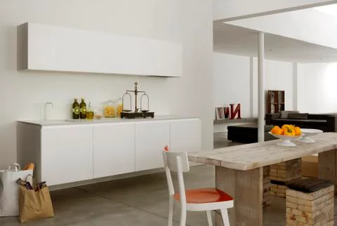 Modern and eclectic white kitchen with a wood table and stools Stock Photos