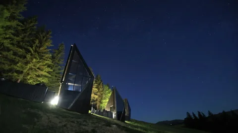 Modern angular cabins stand beneath a clear star filled night sky, Exterior Vidéo 340032235