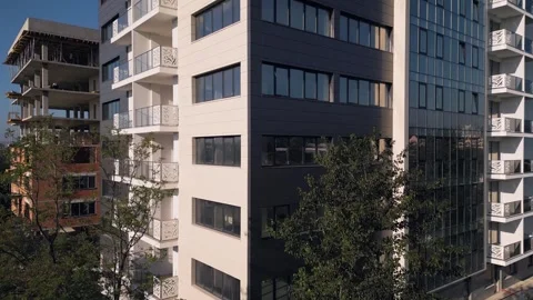 Modern apartment building facade next to construction site under clear sky Stock Footage 346233136