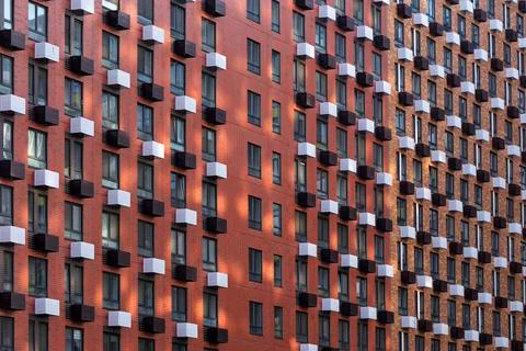Modern apartment building facade with repeating dark windows and small balc.. Stock Photos