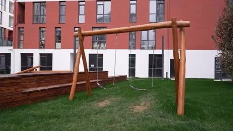 Modern Apartment Facade with Empty Swings in the Yard - Downward Camera Tilt Stock Footage 311638579