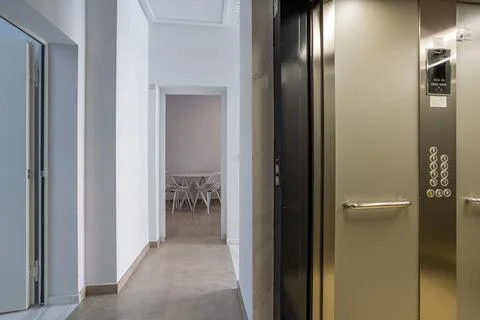 Modern apartment hallway with open elevator and view into dining area Stock Photos