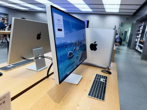 Modern Apple computer lab with iMacs on wooden desks in a bright tech space Stock Photos