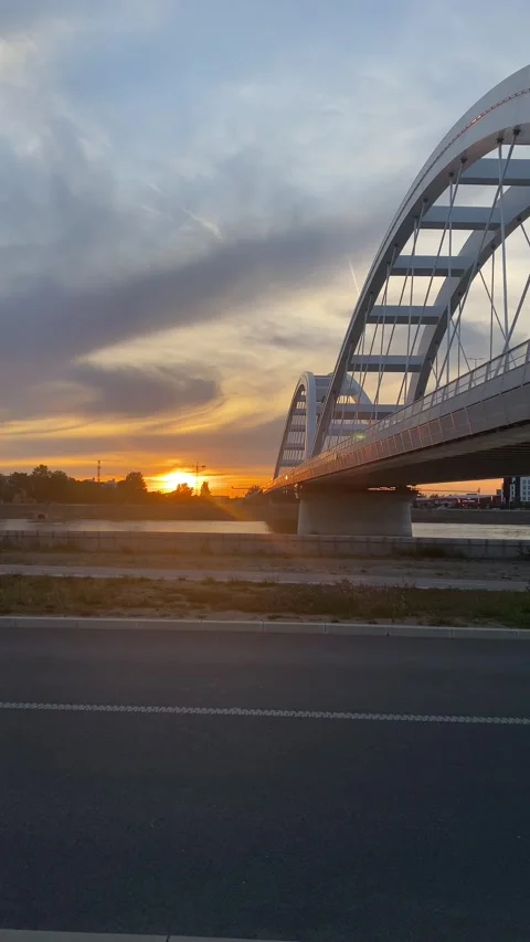 Modern Arch Bridge Over River Sunset Orange Purple Sky Road Foreground Stock Footage 339480121