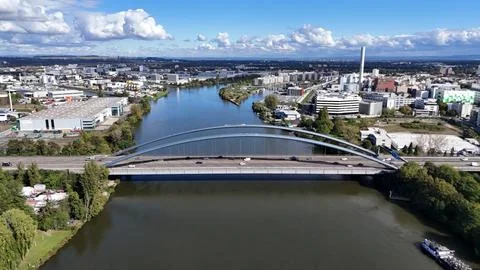 Modern Arch Bridge Over River in Industrial and Urban Area, Aerial View Фото